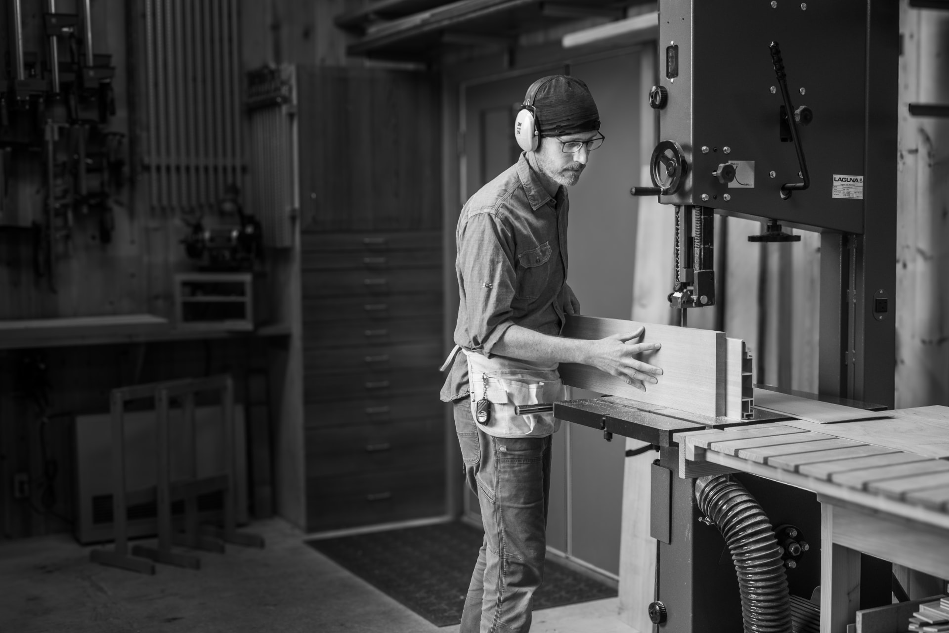 Laël Gordon guiding a thick piece of wood through a large Laguna bandsaw in the workshop